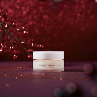 A jar of Intense Barrier Cream on a festive red background with glowing lights and branches