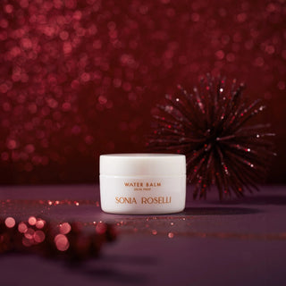 Water Balm Skin Prep on a red surface with a festive, glittery red background and decorative elements